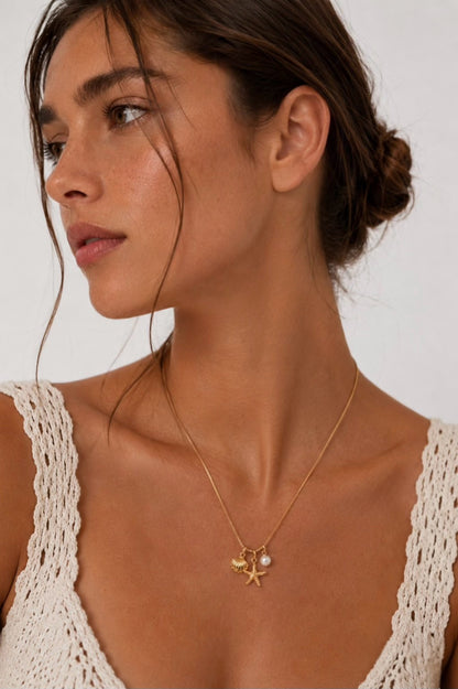 Model wearing Coastal Charm gold starfish, seashell and pearl necklace
