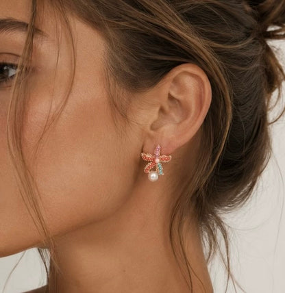 Model wearing Coral Crush colourful gold starfish stud earrings with pearl detail