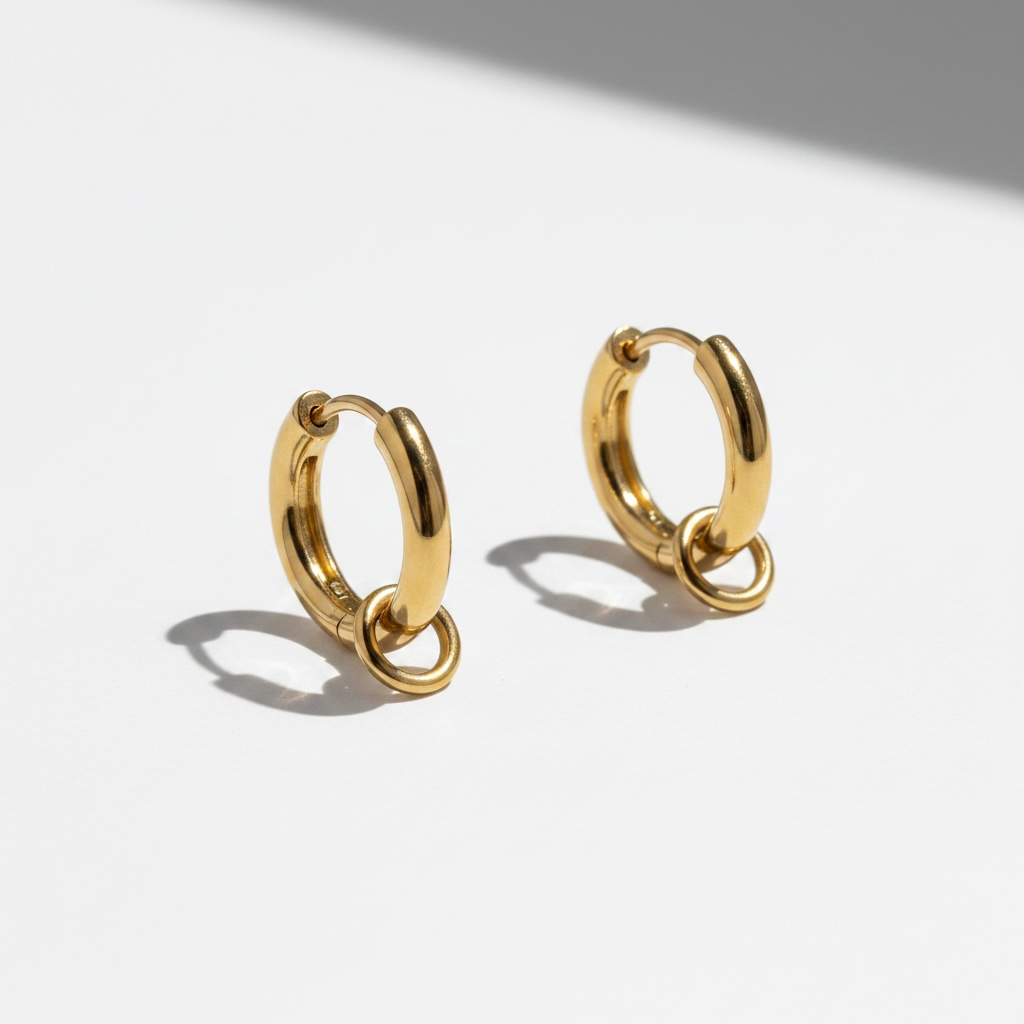 Romy gold huggie earrings with ring detail on white background