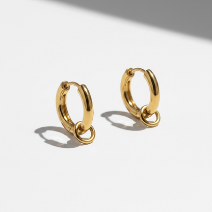Romy gold huggie earrings with ring detail on white background